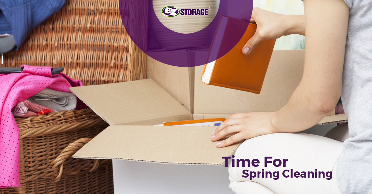 A person putting an orange book inside of a moving box with an open twine basket in the background