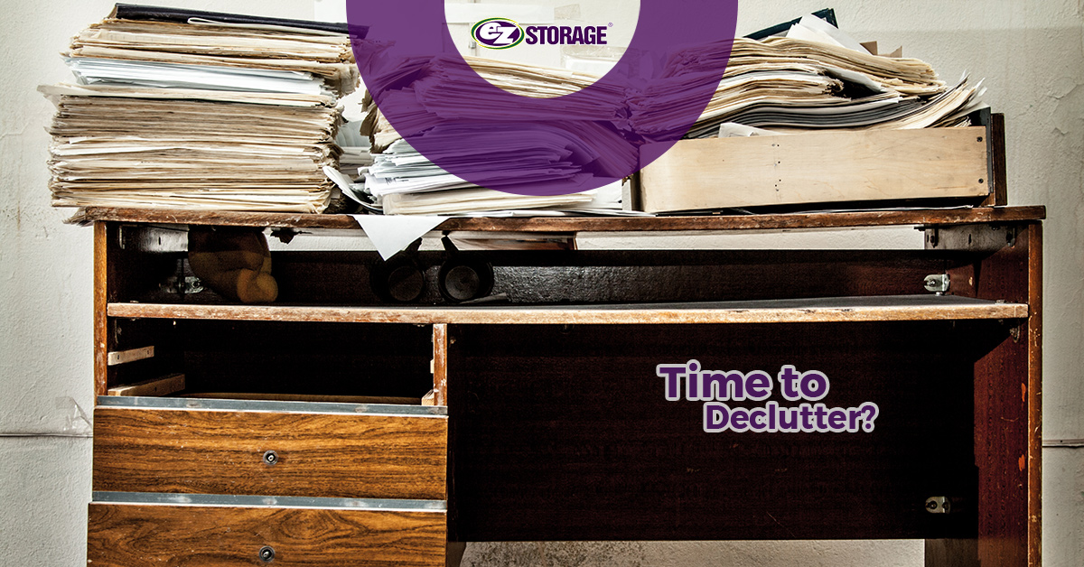 Large amount of paperwork on top of a desk with text "time to declutter"
