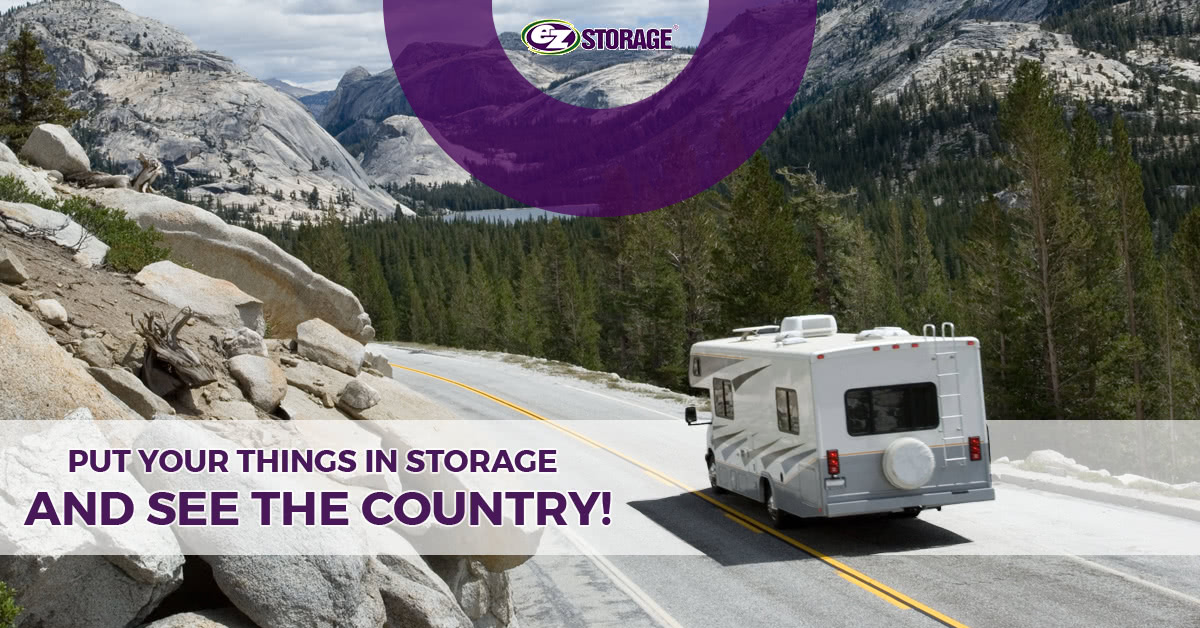 A mobile home driving through a cliffside road with a forest and mountains in the background