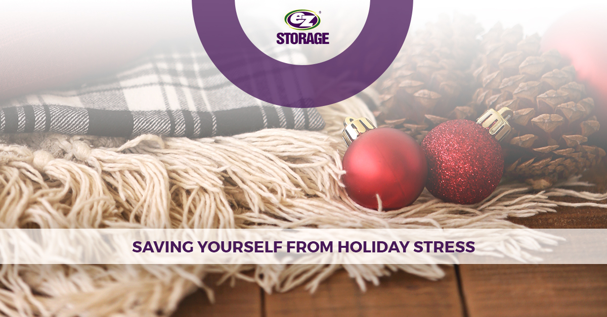 Red ornaments and pine cones on plaid blanket with EZ Storage logo and text "Saving Yourself From Holiday Stress"