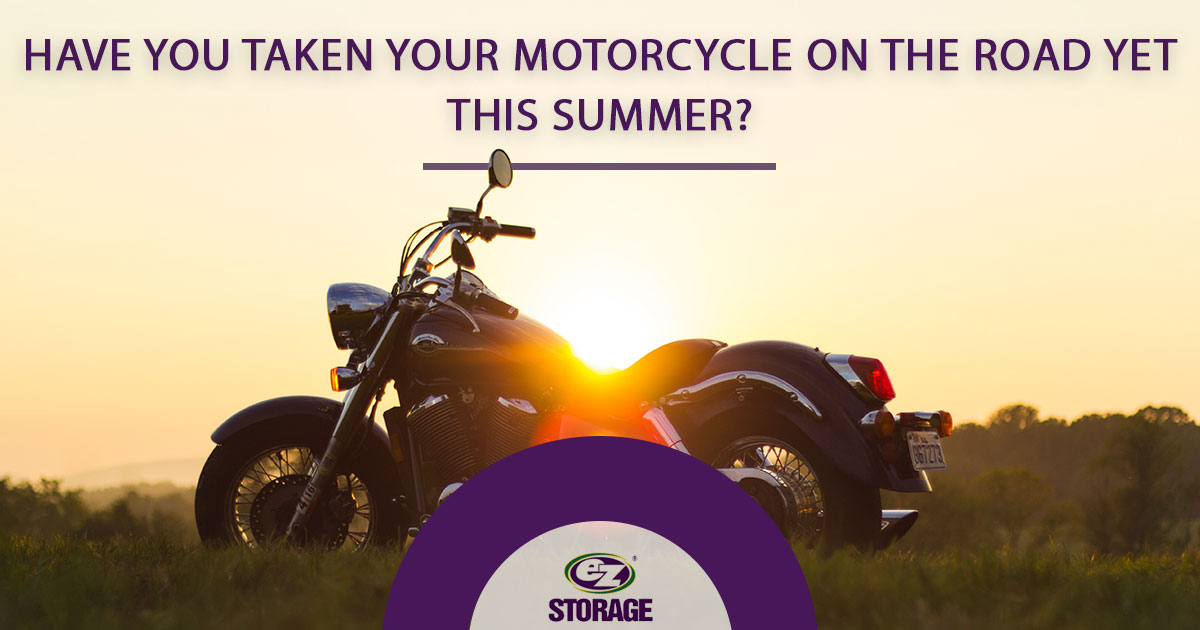 Motorcycle parked on grassy field with text "have you taken your motorcycle on the road yet this summer?"