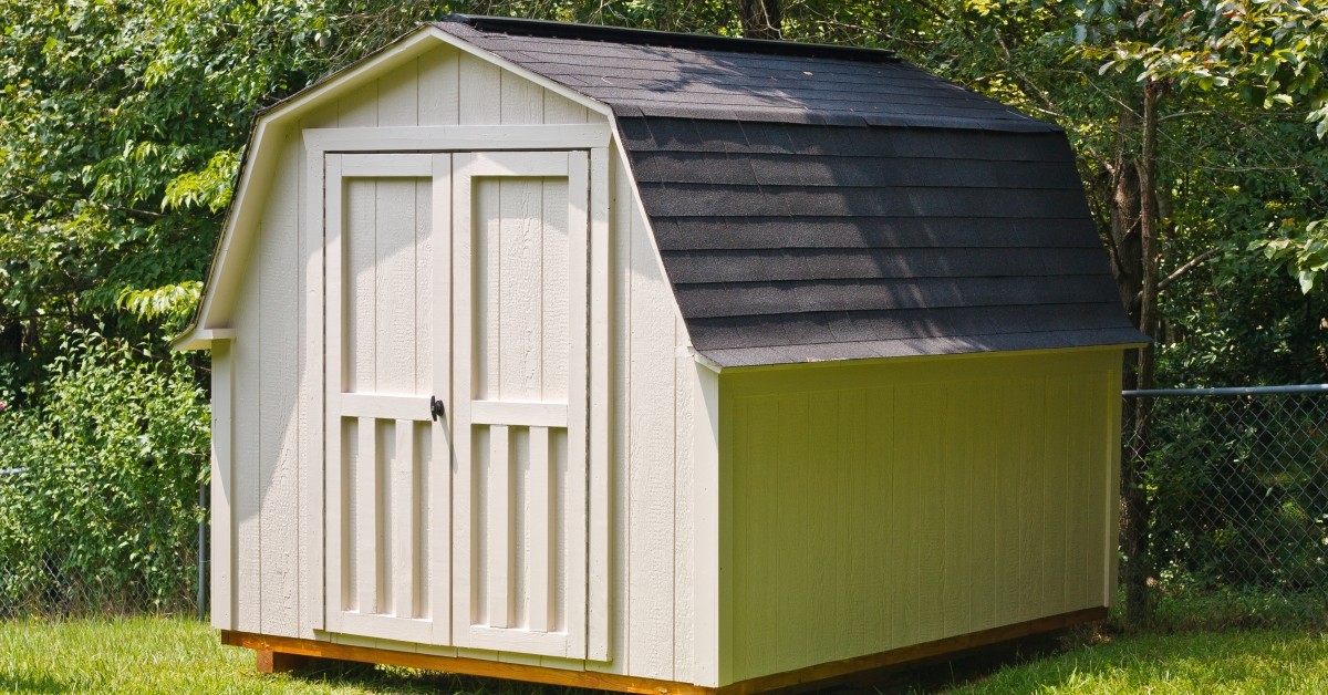 Backyard shed with gray shingled roof and beige paint