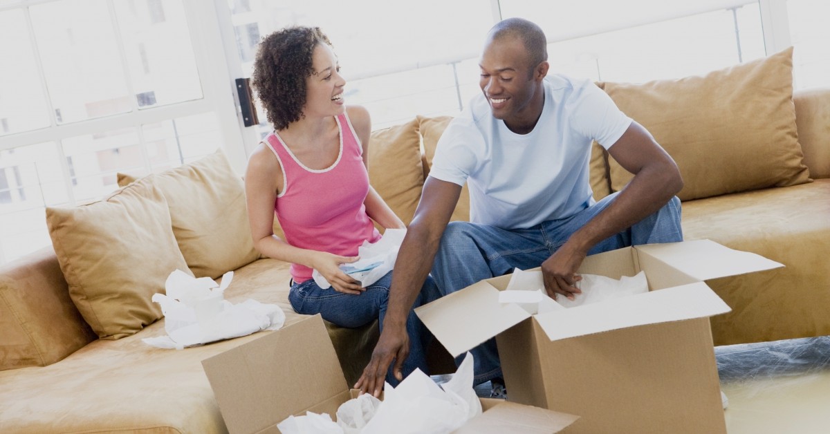 Man and woman smiling while packing items into moving boxes