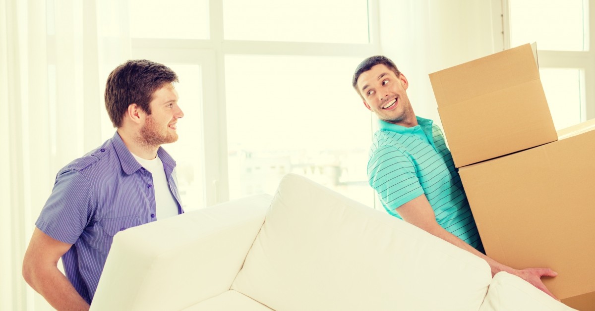 Two men moving a couch and boxes into new apartment
