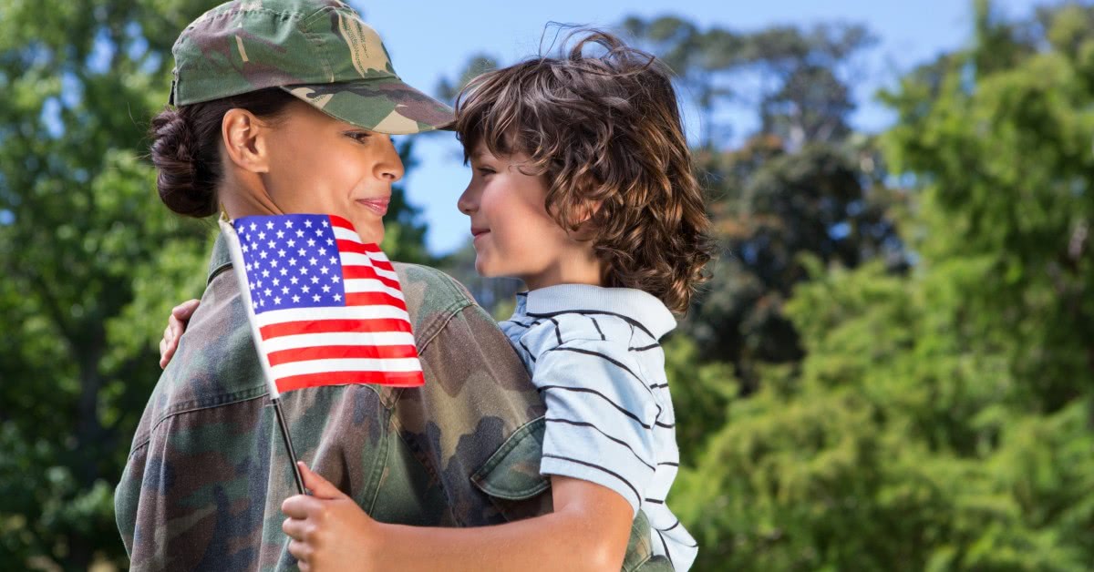 Woman in military fatigues hugging young boy