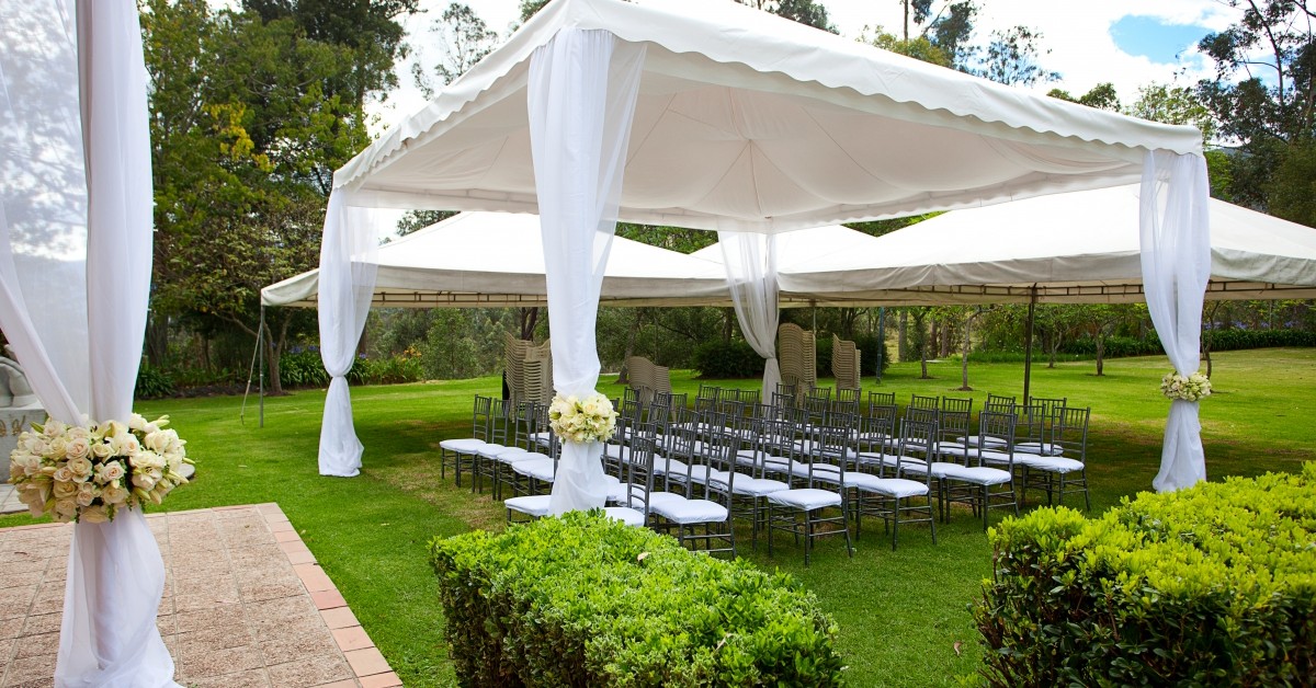 Setting for an outdoor wedding with white canopied seating and alter
