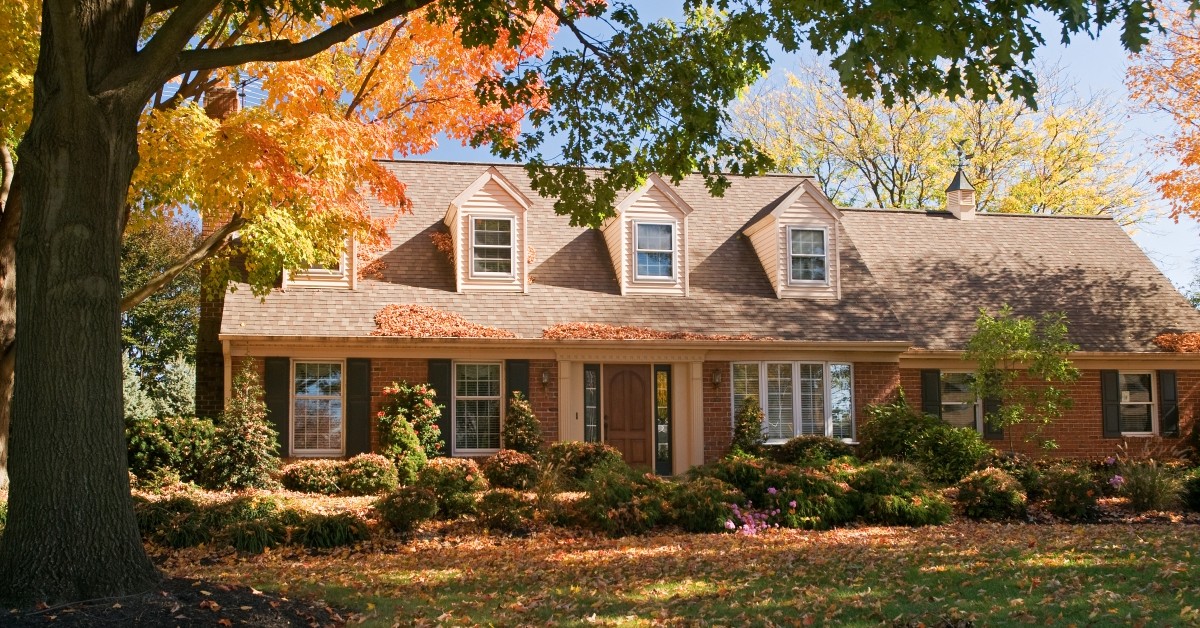 Frontal view of a Cape Cod-style home with gables during the fall with changing leave colors