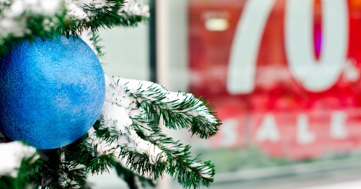 Close up of a blue ornament on a Christmas tree branch outside of a store-front