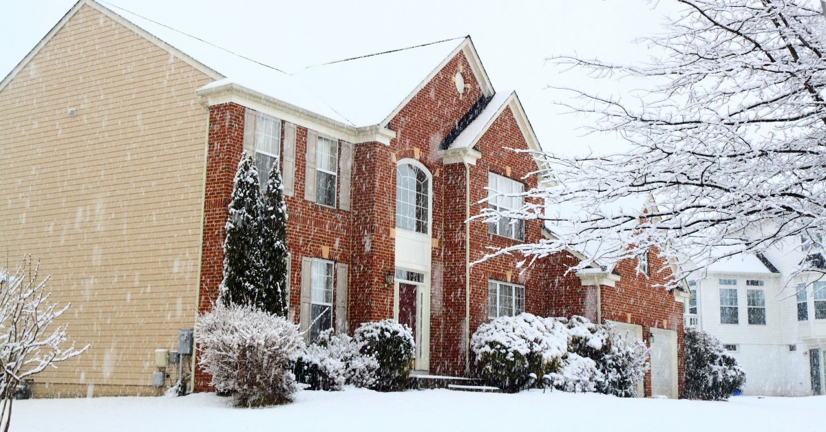 Frontal/side view of residential two-story brick home during a heavy snow.