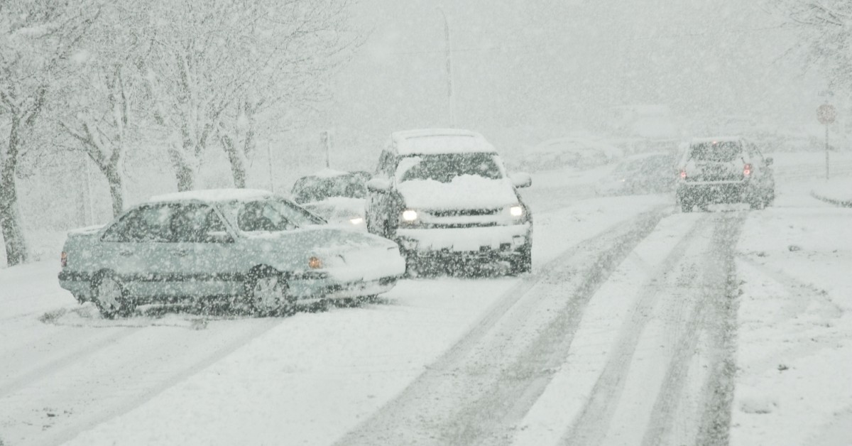 Four passenger vehicles on the road during a hazardous snow storm.