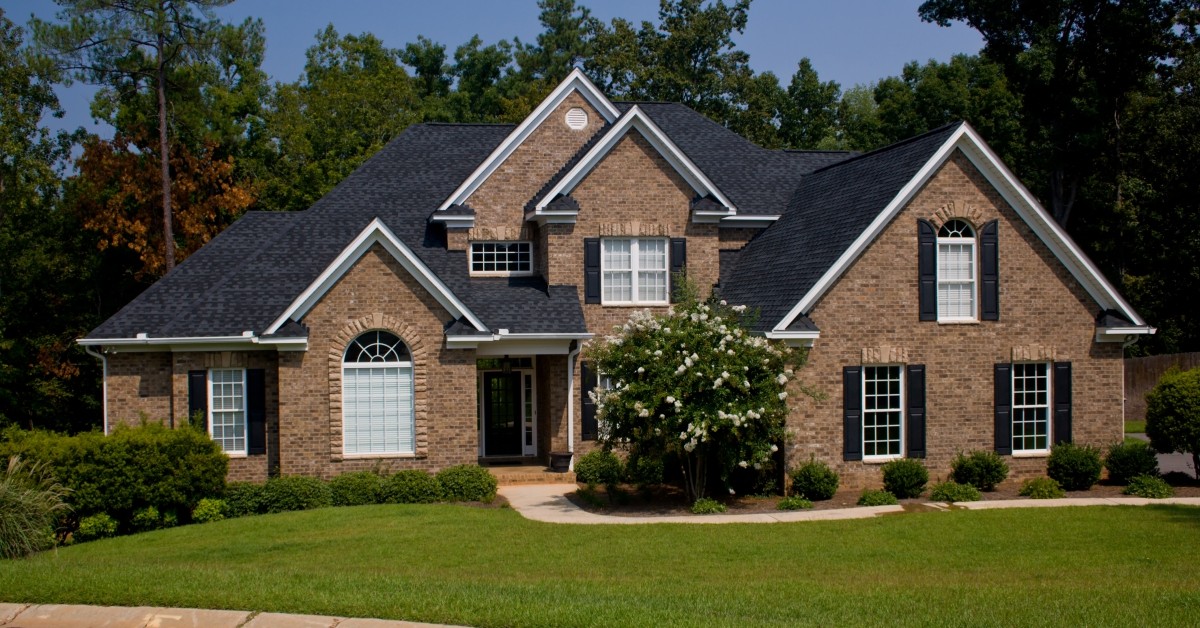 Front&nbsp;view of a two-story residential home with gables, manicured green lawn and driveway.
