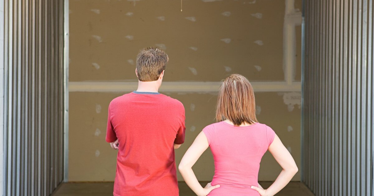Man and woman looking into an empty storage unit with backs to camera