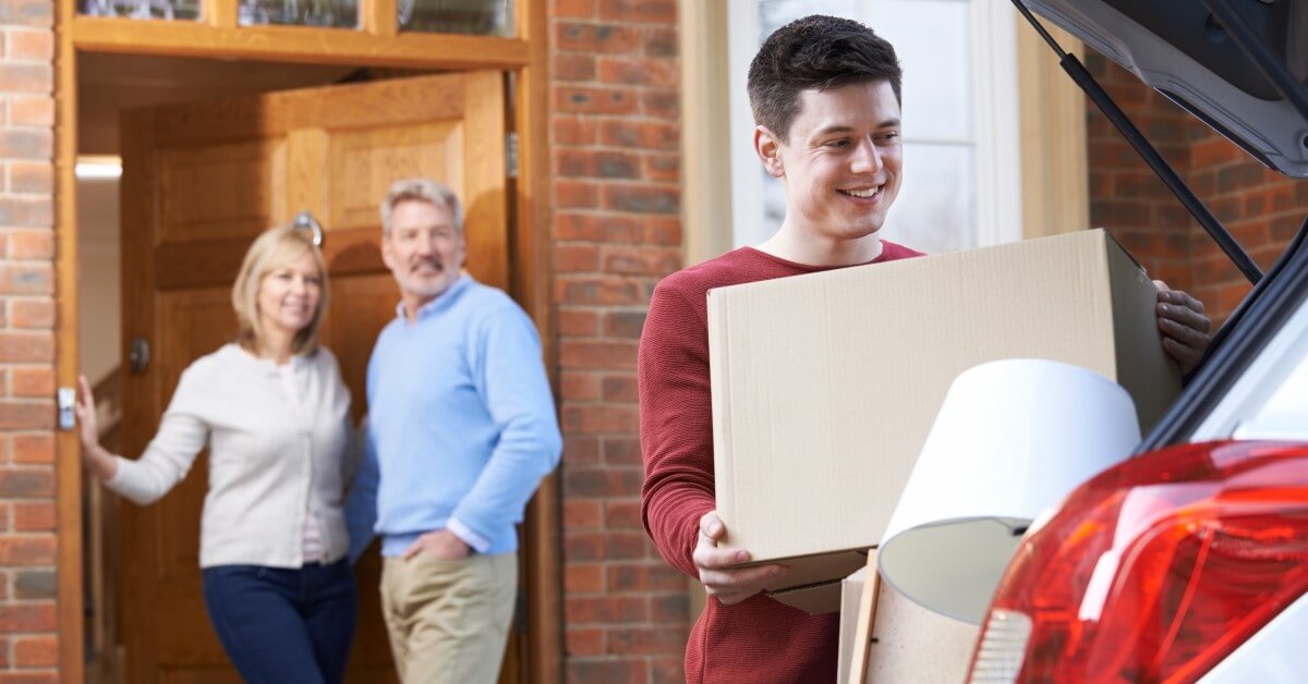Student loading boxes into truck with parents in background