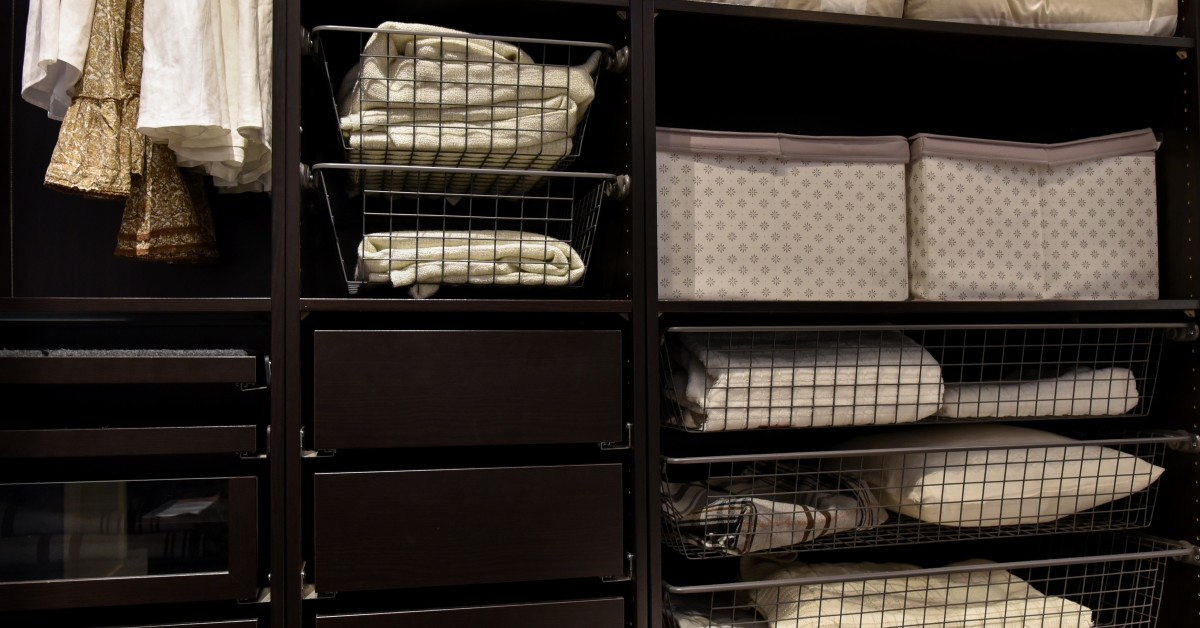 Interior shelves of a closet organizer with pillows and personal items in shelves.