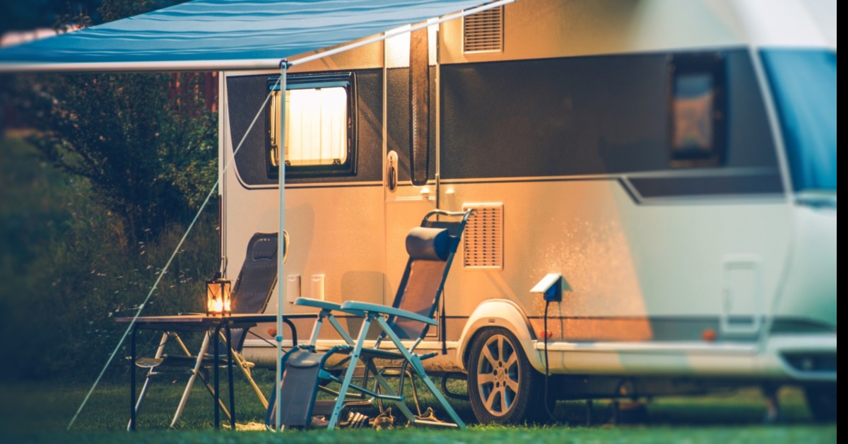 RV with cover open and camp chairs next to table