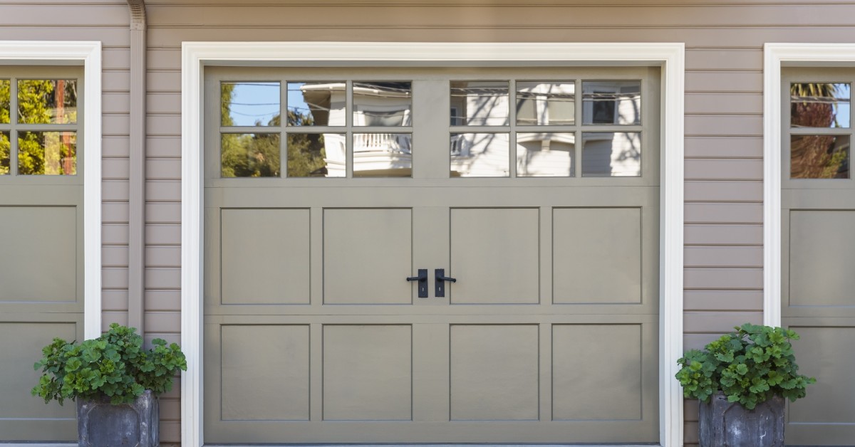 Light green garage door with handles and two potted plants